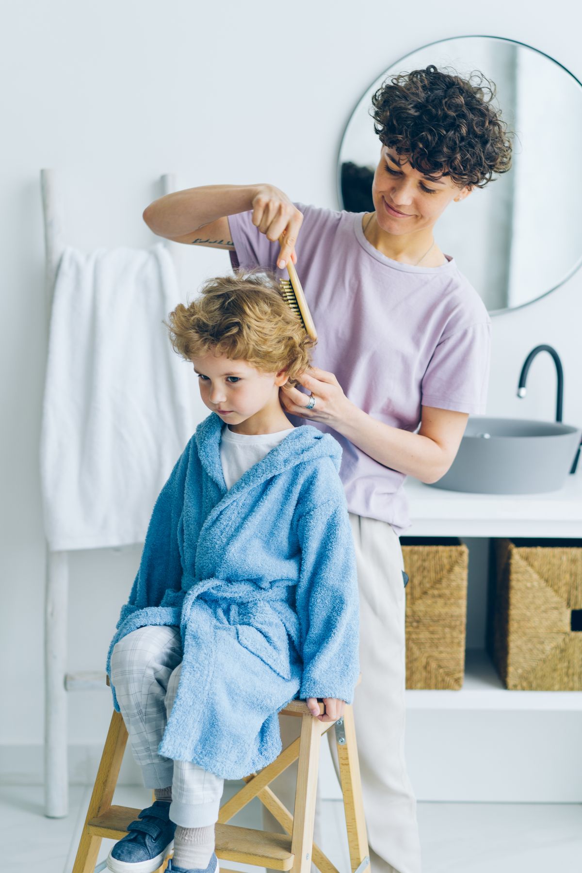 A woman gently combing a young child's hair